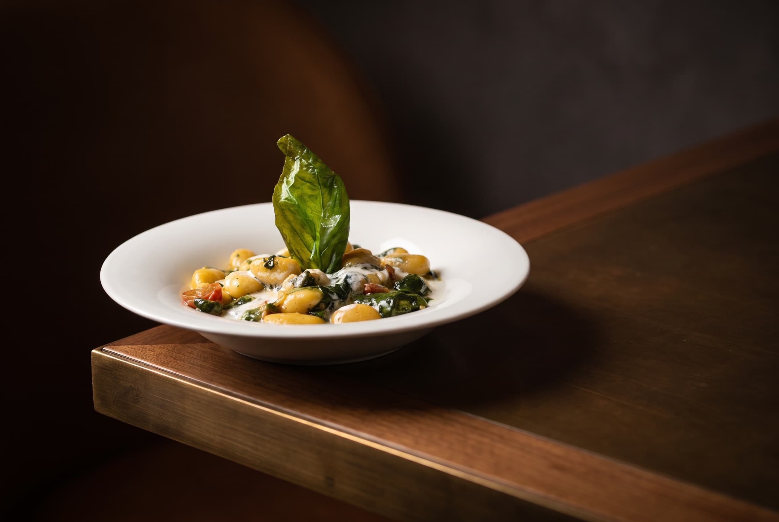 Gnocchi fatti in casa con crema di burrata, spinaci, pomodorini confit e basilico fritto