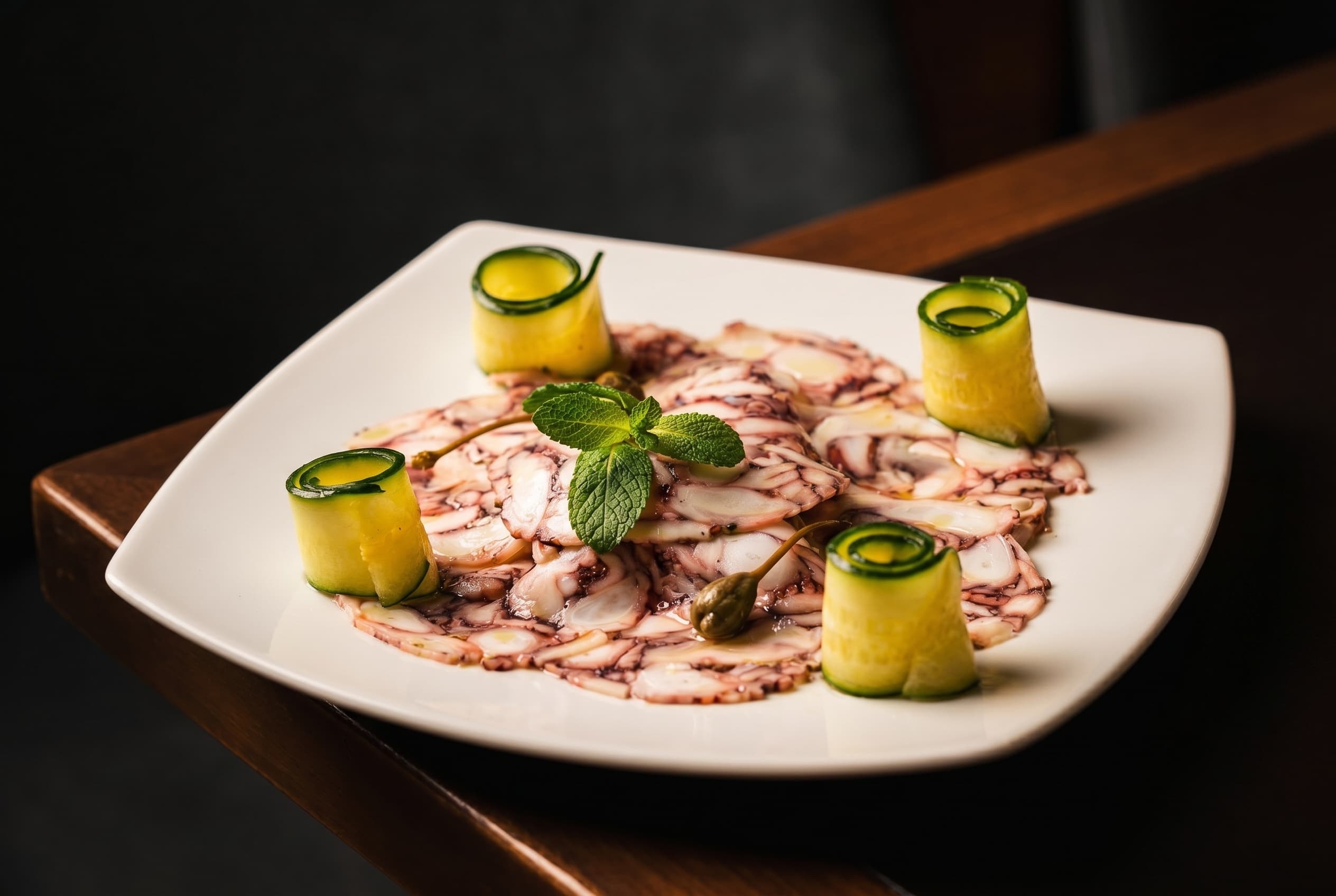 Carpaccio di polpo con riccioli di zucchina, menta e capperi